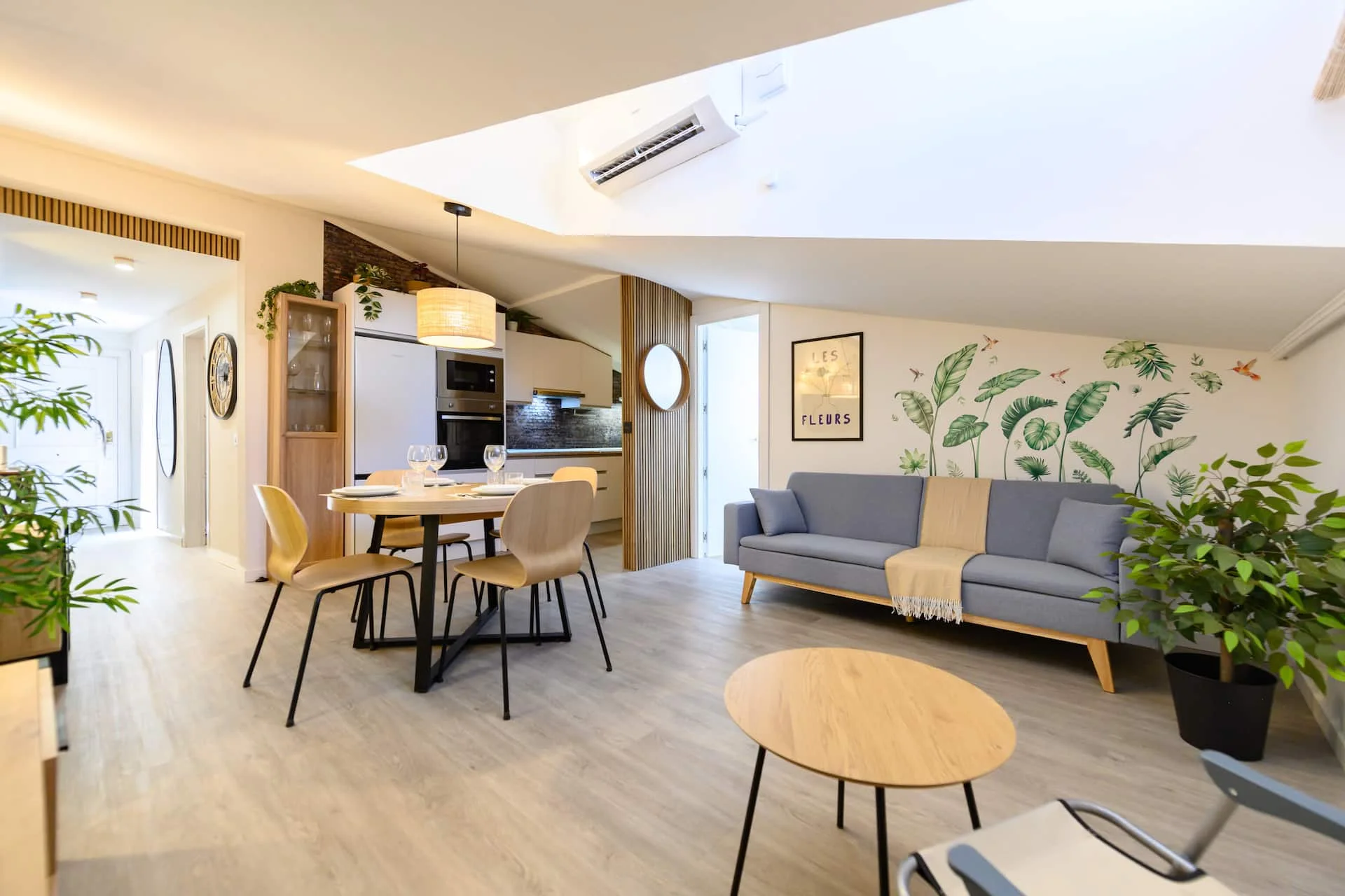 Salón con sofá gris, mesa de comedor y plantas